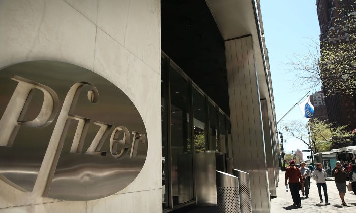People walk past the Pfizer logo on their world headquarters in Manhattan, New York City, on May 5, 2014. (Spencer Platt/Getty Images)