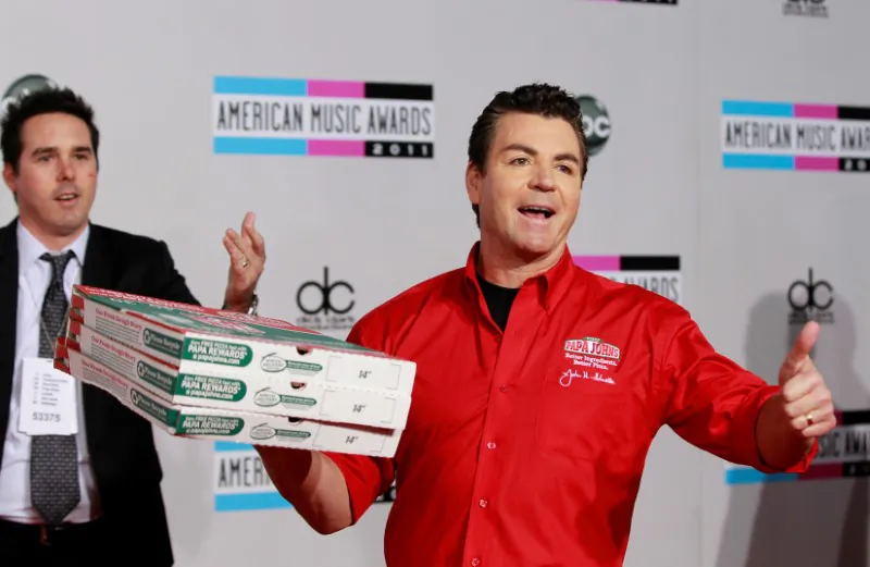 John Schnatter (R), founder and chief executive of Papa John's Pizza, arrives at the 2011 American Music Awards in Los Angeles November 20, 2011. (Reuters/Danny Moloshok/File Photo)