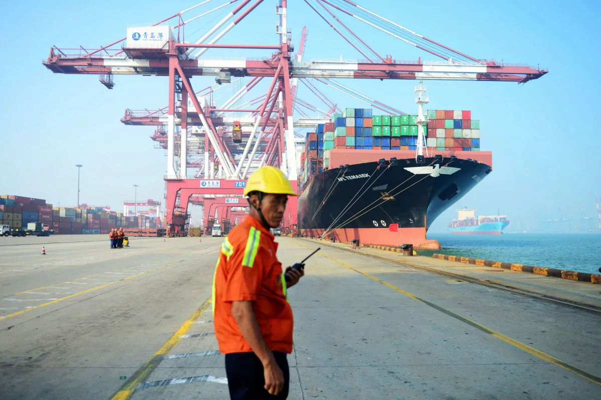 A Chinese worker looks on as a cargo ship is loaded at a port in Qingdao, Shandong Province, China on July 13, 2017.(STR/AFP/Getty Images)