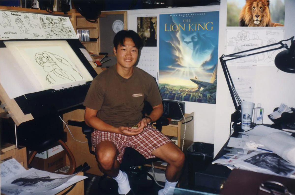 An old photo of Davy Liu in his office at Disney, with a poster of "The Lion King" behind him. "The Lion King" was one of Liu's favorite projects. (Courtesy of Davy Liu)