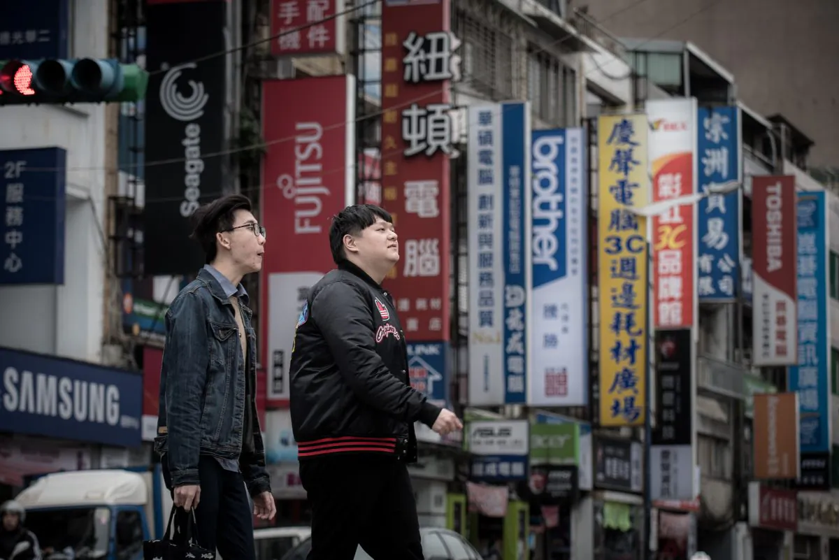 Pedestrians cross a street lined with the signs of electronic brands in Taipei on Jan. 12, 2016. China has announced a whopping list of new economic benefits designed to lure Taiwanese businesses and individuals to the mainland. (Philippe Lopez/AFP/Getty Images)