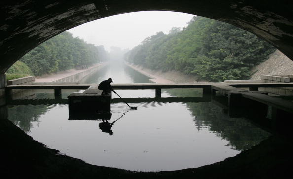 A worker gathers rubbish on the moat around the Old City Wall in Xian of Shaanxi Province, on August 23, 2006. (China Photos/Getty Images)