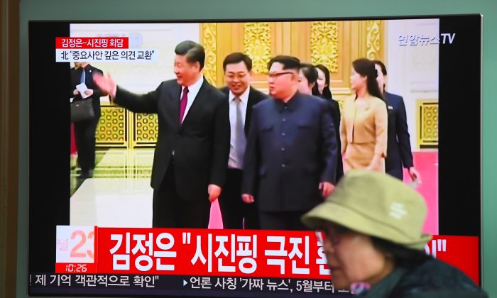 A woman walks past a television news screen reporting about a visit to China by North Korean leader Kim Jong Un, at a railway station in Seoul on March 28, 2018. During the visit, just prior to Kim’s summit with President Donald Trump, Chinese leader Xi Jinping (pictured with Kim) showered the North Korean dictator with nearly $400,000 in gifts, violating U.N. sanctions.  (JUNG YEON-JE/AFP/Getty Images)
