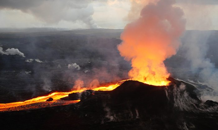Early morning view of fissure 8 and lava channel looking toward the east. The laze plume from the ocean entry is visible in distance (left of the fissure 8 plume) on July 14, 2018. (USGS)