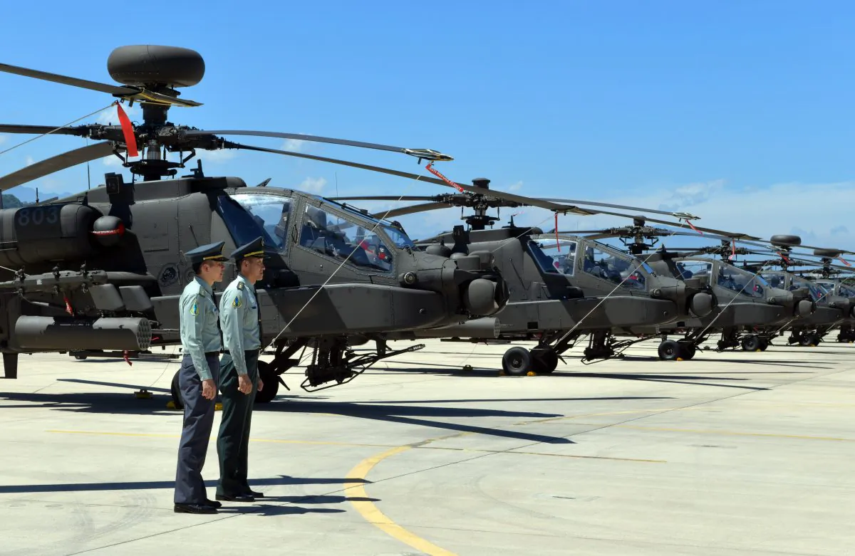 Two Taiwan servicemen stand in front of U.S.-made Apache AH-64E attack helicopters during a commissioning ceremony at a military base in Taoyuan City, Taiwan, on July 17, 2018. (Sam Yeh/AFP/Getty Images)
