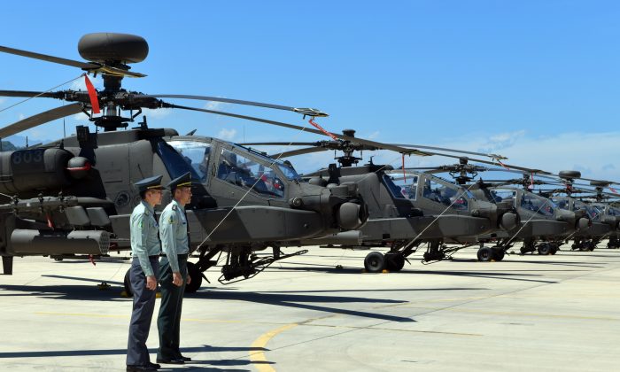 Two Taiwan servicemen stand in front of U.S.-made Apache AH-64E attack helicopters during a commissioning ceremony at a military base in Taoyuan City, Taiwan, on July 17, 2018. (Sam Yeh/AFP/Getty Images)