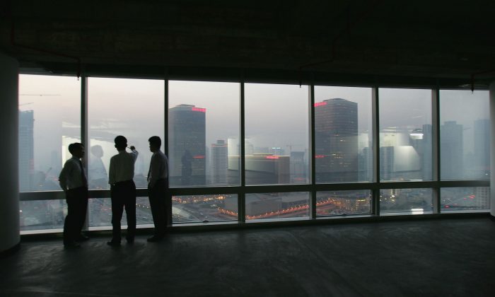 Office workers look out at the Central Business District in Beijing from inside a newly developed office building on Nov. 18, 2004. (Cancan Chu/Getty Images)