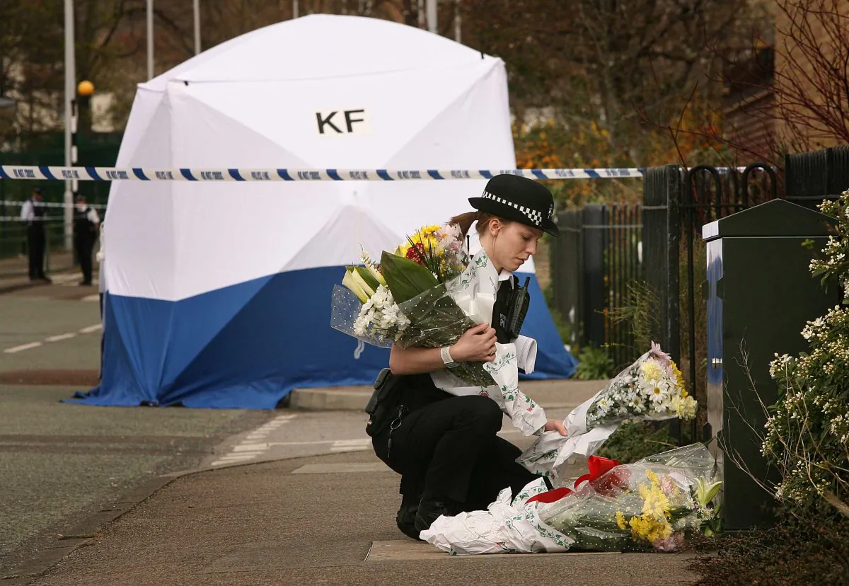 A police woman places floral tributes near a tent covering the murder scene in Leytonstone in north-east London on April 7, 2007. (Peter Macdiarmid/Getty Images)
