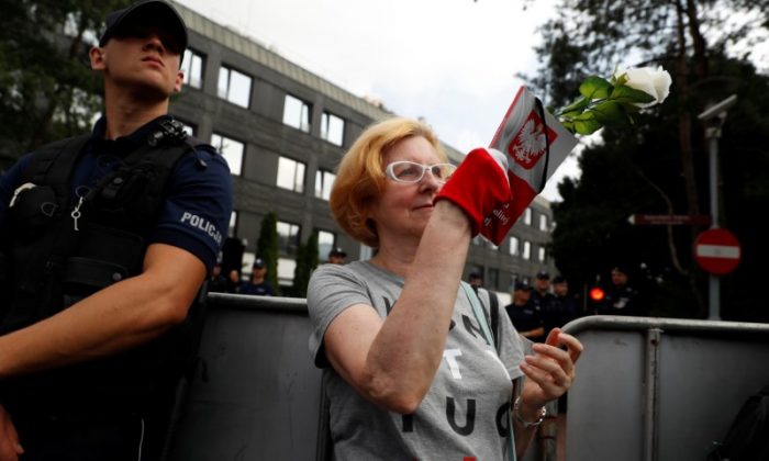 A woman holds a copy of the Polish constitution as she takes part in a protest in support of free courts outside the Parliament building in Warsaw July 18, 2018. (REUTERS/Kacper Pempel)