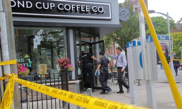 Police officers enter a coffee shop damaged by gunfire while investigating a mass shooting on Danforth Avenue in Toronto, Canada, July 23, 2018.  (Reuters/Chris Helgren)