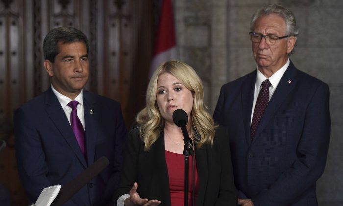 Conservative MP Michelle Rempel stands with MPs Pierre Paul-Hus (L) and Larry Maguire as she speaks to reporters ahead of an emergency meeting of the Citizenship and Immigration Committee on Parliament Hill in Ottawa on July 16, 2018. (The Canadian Press/Justin Tang)