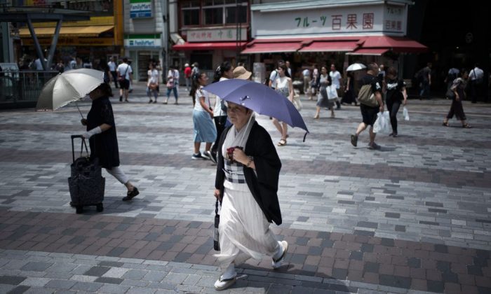 A woman holds an umbrella as she walks along a street in Tokyo on July 23, 2018, as Japan suffers from a heatwave. (Martin Bureau/AFP/Getty Images)