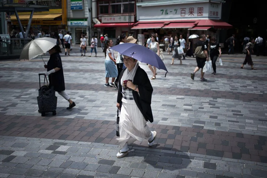 A woman holds an umbrella as she walks along a street in Tokyo on July 23, 2018, as Japan suffers from a heatwave. (Martin Bureau/AFP/Getty Images)
