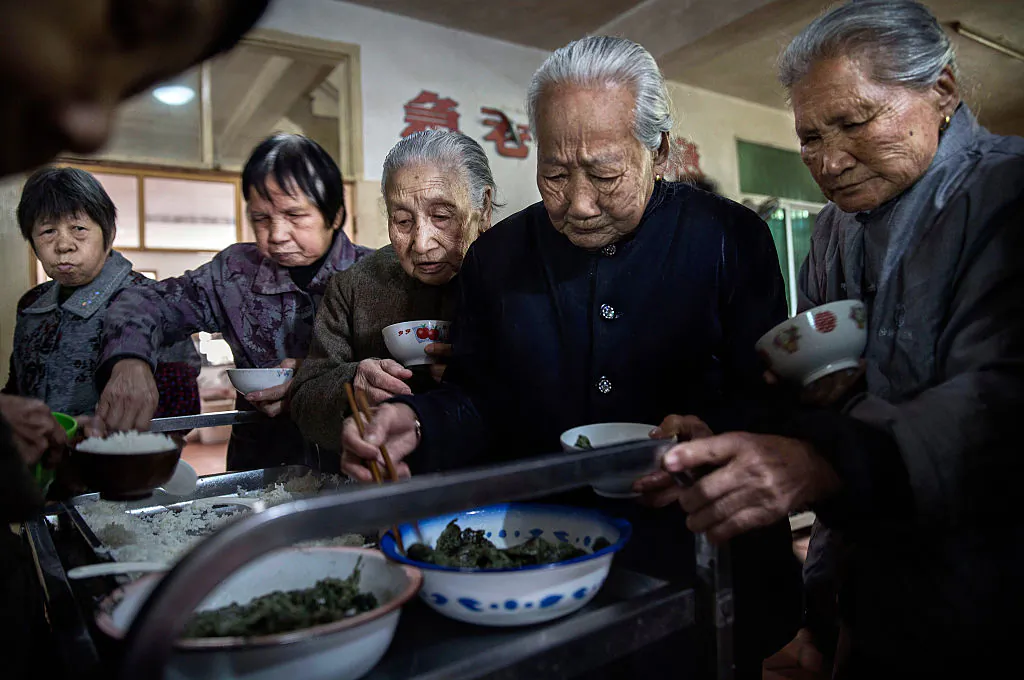 Elderly Chinese people serve themselves lunch at a nursing home in Sha County, Fujian Province, China, on March 17, 2016. (Kevin Frayer/Getty Images)