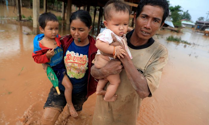 Parents carry their children as they leave their home during the flood after the Xepian-Xe Nam Noy hydropower dam collapsed in Attapeu province, Laos  July 26, 2018. (Retuers/Soe Zeya Tun)