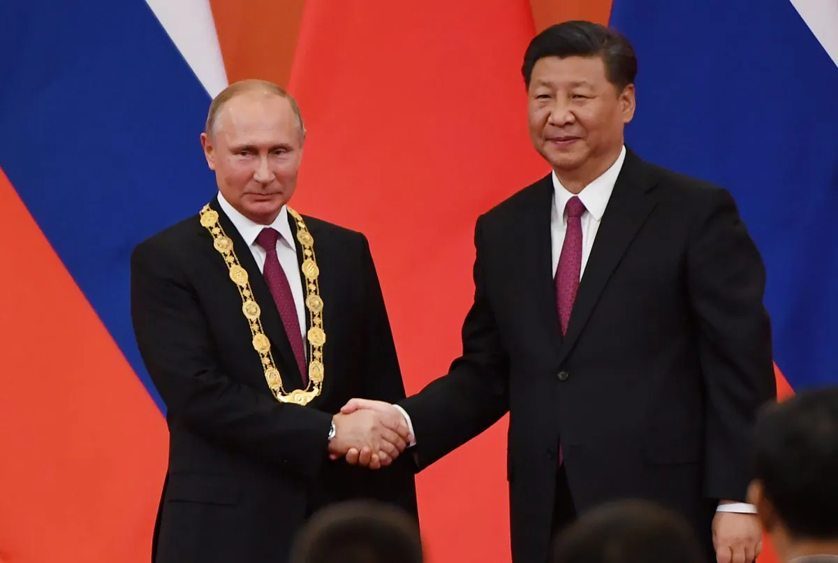 Chinese Communist Party leader Xi Jinping (R) congratulates Russian leader Vladimir Putin after presenting him with the Friendship Medal in the Great Hall of the People in Beijing on June 8, 2018. (Greg Baker/AFP/Getty Images)