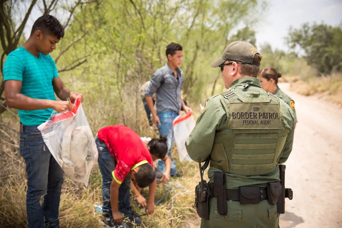 Border Patrol agents get illegal immigrants to put their belongings into plastic bags before transporting them to a processing facility, in Hidalgo County, Texas, on May 26, 2017. (Benjamin Chasteen/The Epoch Times)