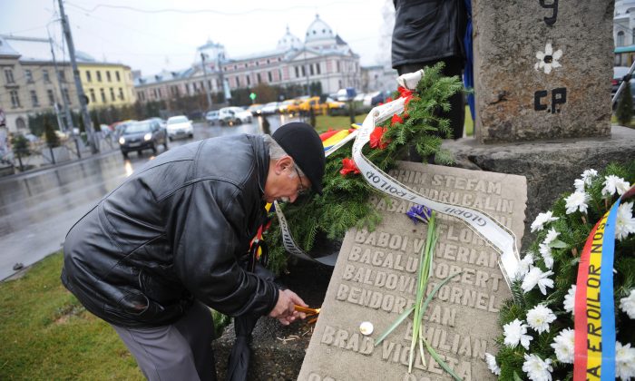 A man light candles during a commemoration ceremony in Bucharest on Dec. 21, 2011, next to a stone bearing names of people killed by communist regime forces in 1989. (Daniel Mihailescu/AFP/Getty Images)