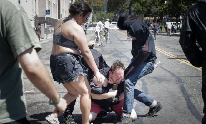 Two people dressed in black beat a man accused of being a right-wing Trump supporter at MLK Jr. Park in Berkeley, Calif., on Aug. 27, 2017. (Elijah Nouvelage/Getty Images)