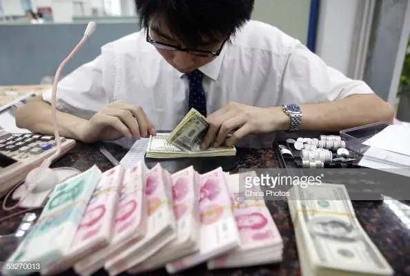 A clerk counts stacks of Chinese yuan and U.S. dollars at a bank in Shanghai on July 22, 2005. (China Photos/Getty Images)