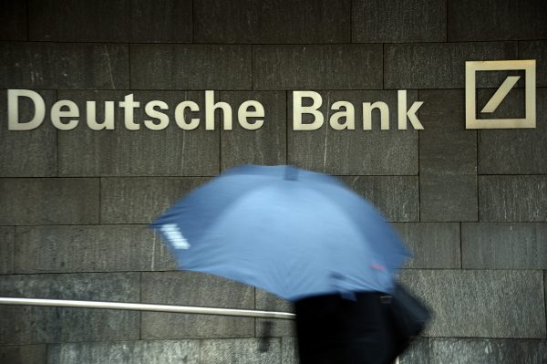 A woman with a umbrella passes a logo of Deutsche Bank on January 29, 2013 in Frankfurt am Main, Germany.