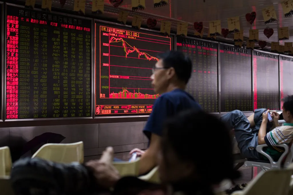 People sit in front of a screen showing stock prices at a brokerage company in Beijing on July 11. (Nicolas Asfouri/AFP/Getty Images)