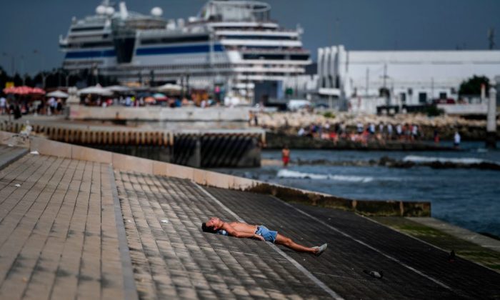A man sunbathes at Ribeira das Naus in Lisbon on Aug. 3, 2018. (Patrica De Melo Moreira/AFP) 