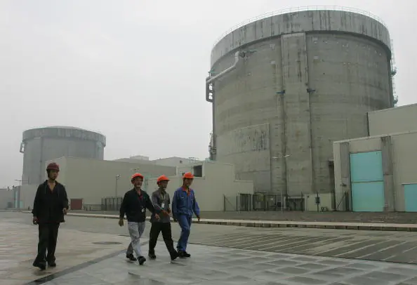 Workers at the Qinshan nuclear power plant walk past containment structures hosing nuclear reactors, in Jiaxing City, Zhejiang Province, on June 10, 2005. (Frederic J. Brown/AFP/Getty Images)