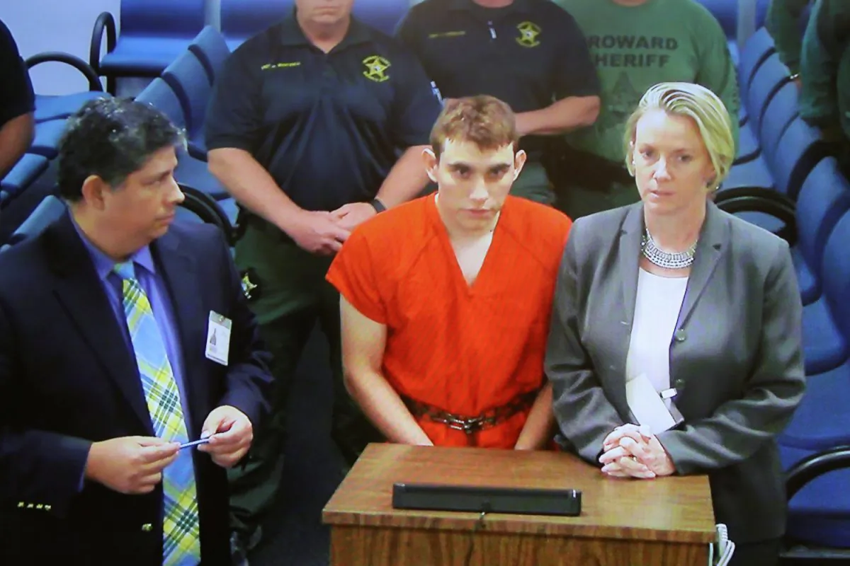 Nikolas Cruz (C) appears via video monitor with Melisa McNeill (R), his public defender, at a bond hearing after being charged with 17 counts of premeditated murder, in Fort Lauderdale, Fla., Feb. 15, 2018. (Susan Stocker/Pool/Reuters)