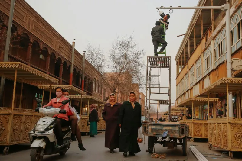 Men install a CCTV camera in a shopping street in the old town of Kashgar, in the Xinjiang region of China on March 23, 2017. (Reuters/Thomas Peter)
