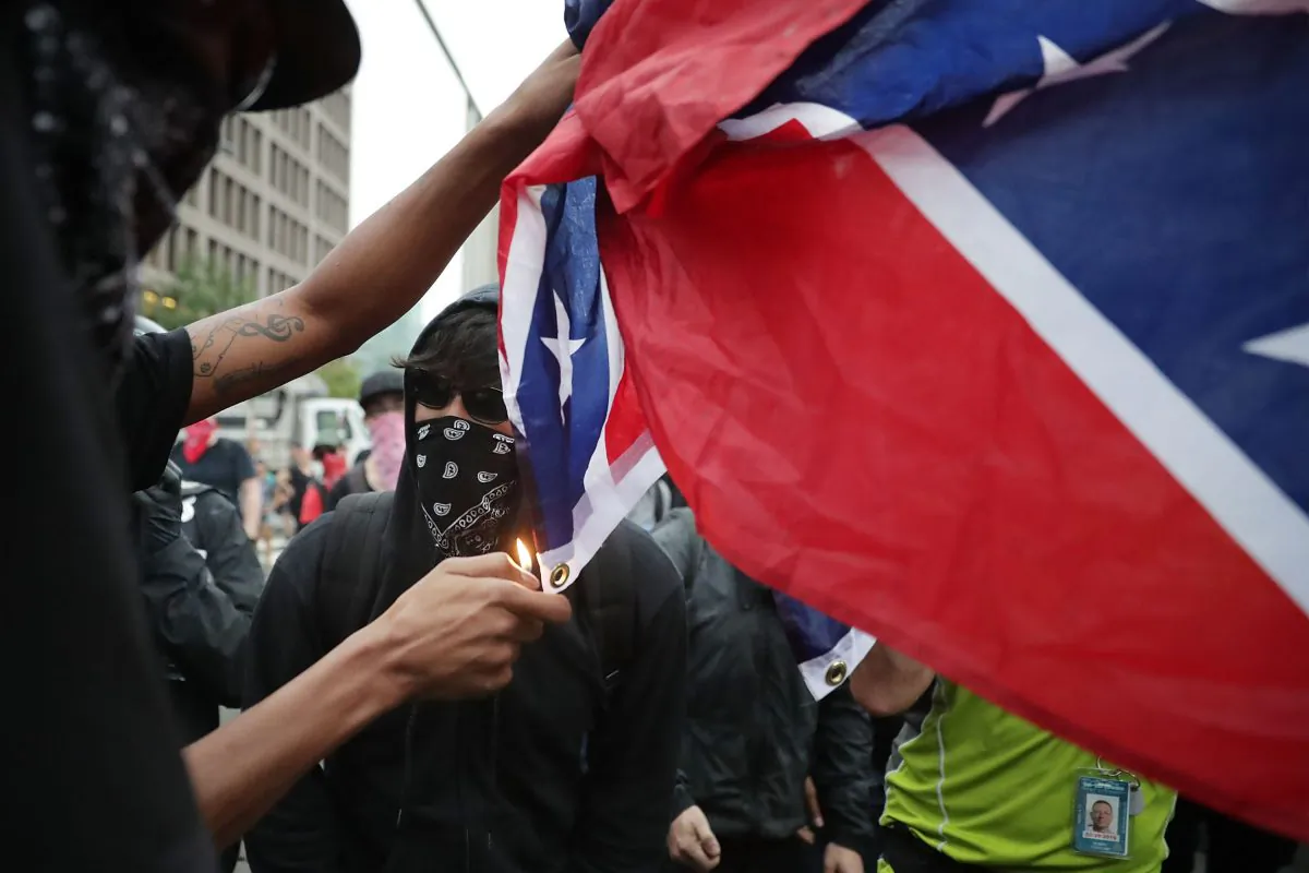 Counter protesters and members of the Antifa and Blac Bloc burn a Confederate battle flag on the east of Lafayette Square where the white supremacist Unite the Right rally is being held in Washington on Aug. 12, 2018. (Chip Somodevilla/Getty Images)