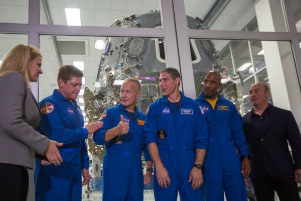 SpaceX President and COO Gwynne Shotwell, NASA Astronauts Bob Behnken, Doug Hurley, Mike Hopkins and Victor Glover, and Director of Crew Mission Management Benji Reed talk after addressing reporters in front of the Crew Dragon spacecraft, under construction in a clean room, during a media tour of SpaceX headquarters and rocket factory on Aug. 13, 2018 in Hawthorne, California.