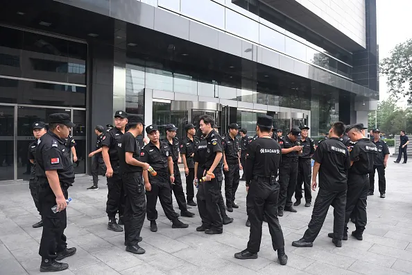 Security personnel stand in front an entrance of China's Banking Regulatory Commission to guard against protesters in Beijing on August 6, 2018. (GREG BAKER/AFP/Getty Images)