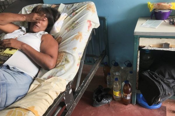 Containers filled with water are seen on the floor next to the bed of a patient at the Central University of Venezuela (UCV) hospital in Caracas, Venezuela on Aug. 14, 2018.
