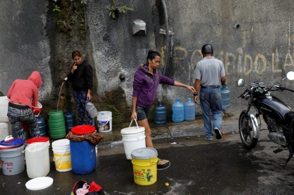 A woman carries a container filled with water coming from a mountain, in a road at Plan de Manzano slum in Caracas, Venezuela on July 20, 2018.