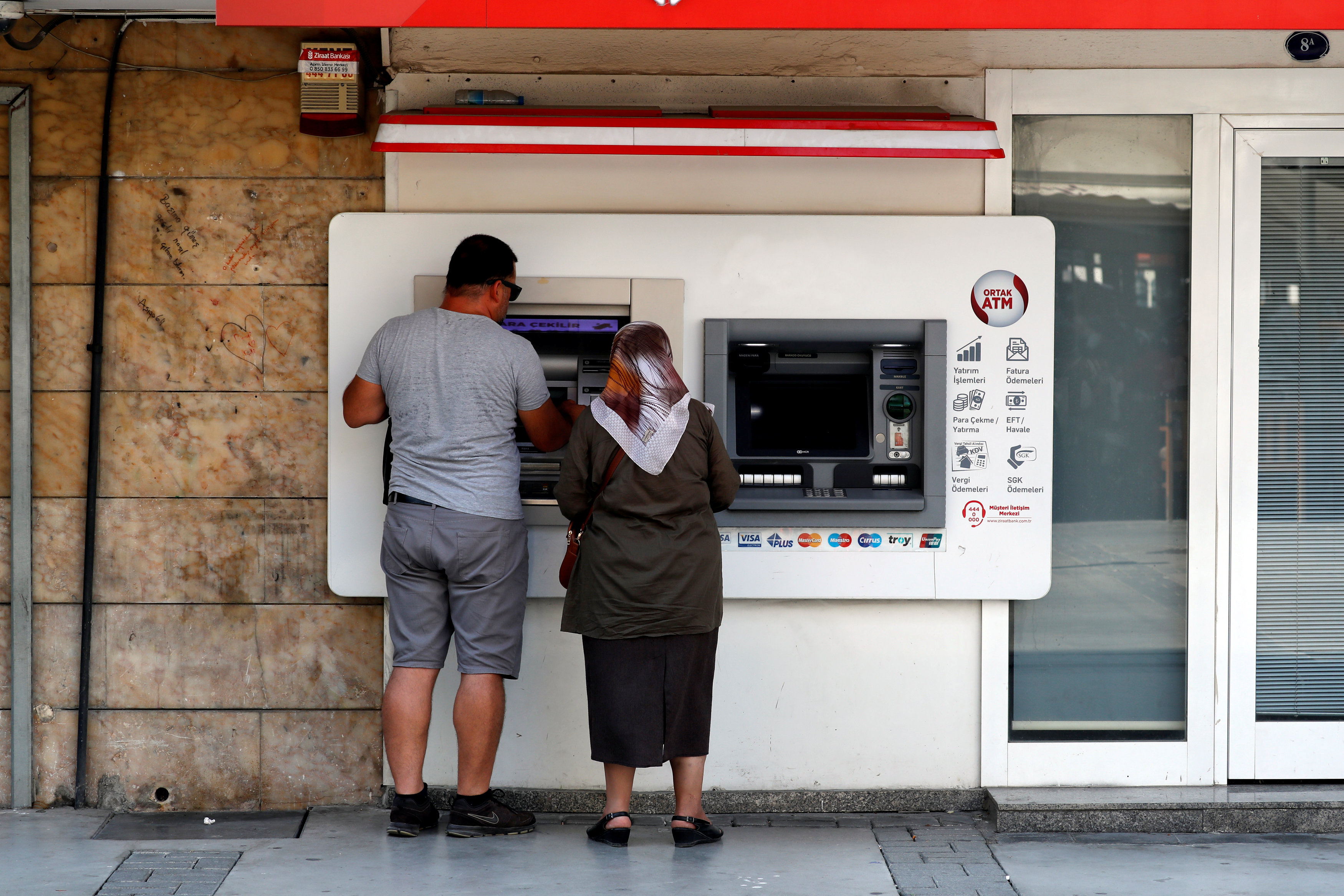 People withdraw money from a bank ATM in Izmir.