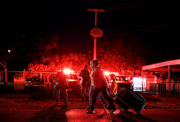 Military officers patrol as Venezuelan women walk towards Santa Elena to sleep, after checking their passports or identity cards at the Pacaraima border control, Roraima state, Brazil August 19, 2018. (Nacho Doce/Reuters)