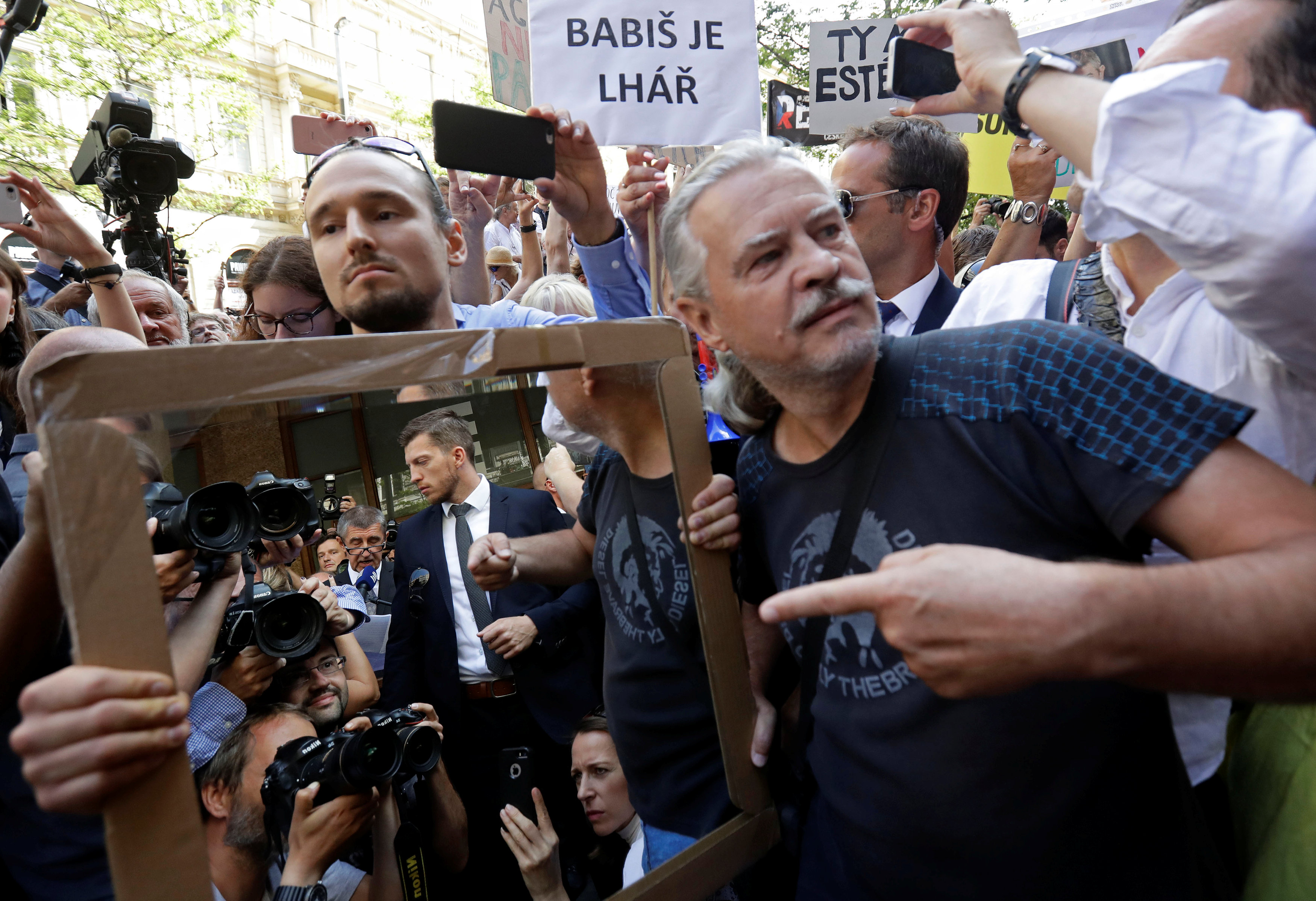 Demonstrators hold a mirror as they protest against Czech Prime Minister.
