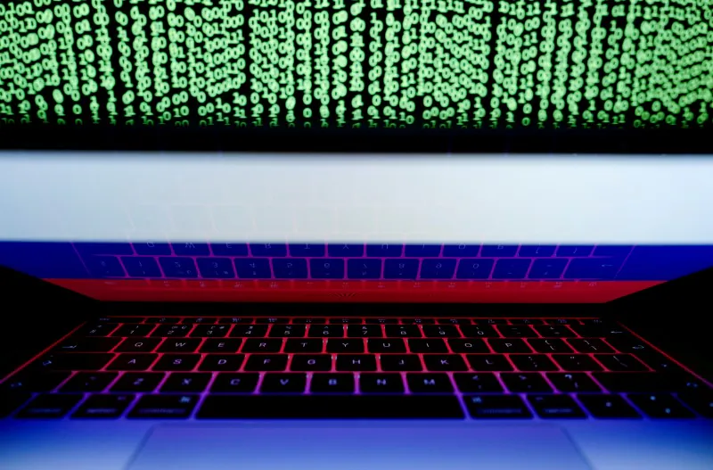 A Russian flag is seen on a laptop screen in front of a computer screen displaying cyber code. (Reuters/Kacper Pempel)