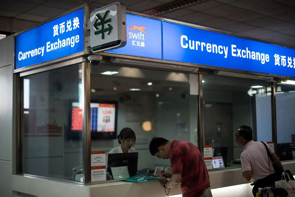A man changes foreign currency into Chinese yuan at a currency exchange office in Hongqiao airport in Shanghai on Aug. 14, 2015. (Johannes Eisele/AFP/Getty Images)