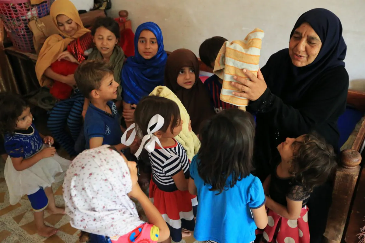 An Iraqi woman Sana Ibrahim al-Taee, 64, whose five sons were killed by ISIS terrorists, play with her grandchildren at her home in Mosul, Iraq July 30, 2018. REUTERS/Ari Jalal