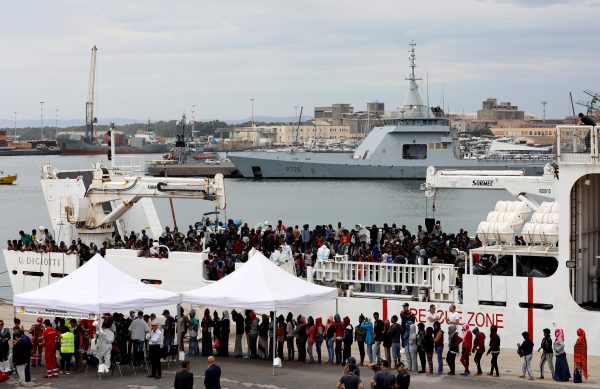 Migrants disembark from a coast guard vessel