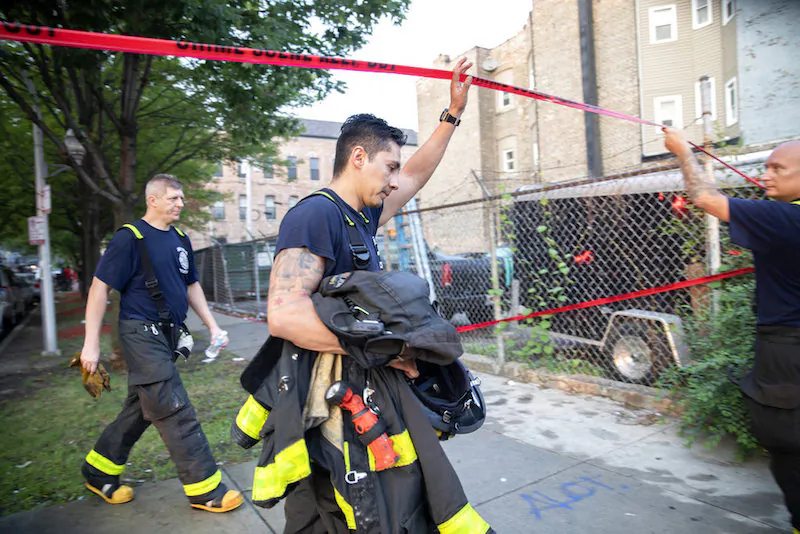 Chicago firefighters walk under tape at the scene of a fire that killed at least 8 people, including 6 children, in the 2200 block of South Sacramento Ave. on Aug. 26, 2018, in the Little Village neighborhood of Chicago. (Erin Hooley/Chicago Tribune)