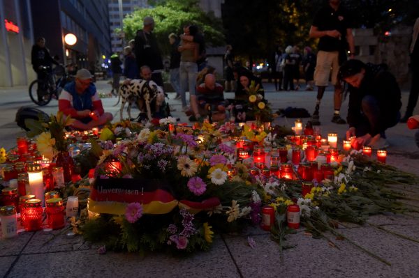 People lay flowers and light candles at the site of a fatal stabbing