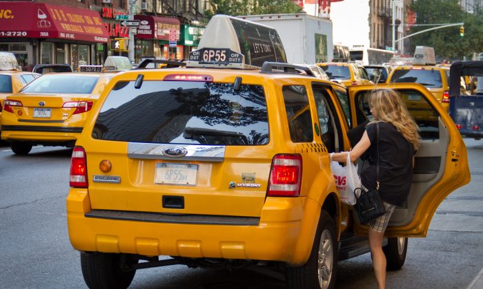 A women climbs into a taxi cab in New York City on July 12, 2012. (Benjamin Chasteen/The Epoch Times)