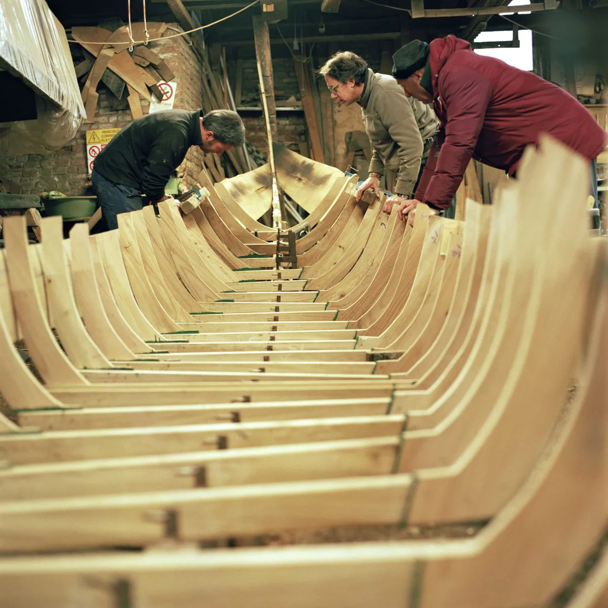 Workers at Domenico Tramontin e Figli inspect the gondola's ribbed frame. (Susanna Pozzoli/Michelangelo Foundation)