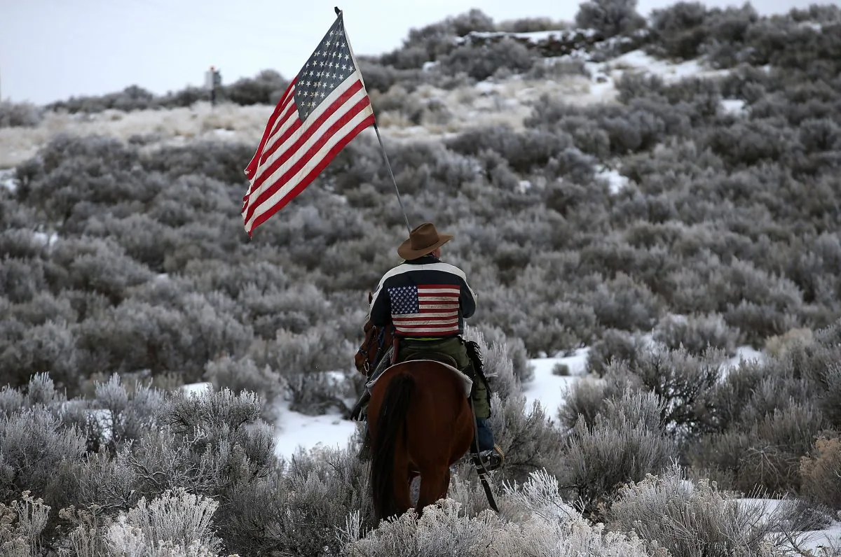 A man carries an American flag as he rides his horse near Burns, Ore., on Jan. 7, 2016. (Justin Sullivan/Getty Images)