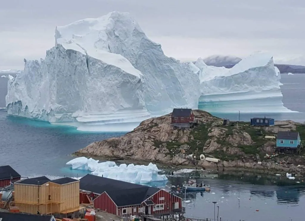 An iceberg behind houses and buildings after it grounded outside the village of Innarsuit, an island settlement in the Avannaata municipality in northwestern Greenland. (Magnus Kristensen/AFP/Getty Images)