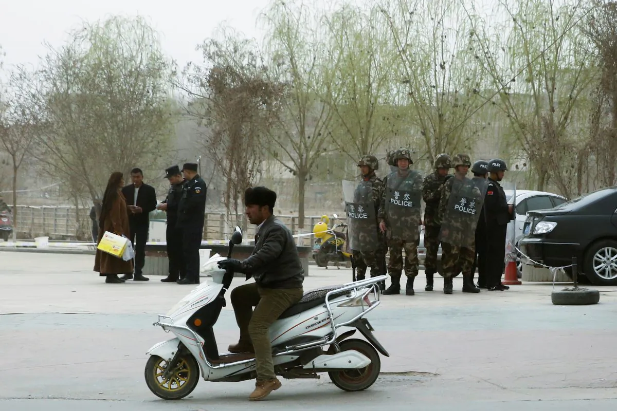 FILE PHOTO: Police officers check the identity cards of a people as security forces keep watch in a street in Kashgar, Xinjiang Uighur Autonomous Region, China, March 24, 2017. REUTERS/Thomas Peter