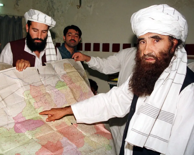 File photo: Jalaluddin Haqqani (R), the Taliban's Minister for Tribal Affairs, points to a map of Afghanistan during a visit to Islamabad, Pakistan, October 19, 2001 while his son Naziruddin (L) looks on. Reuters/File Photo